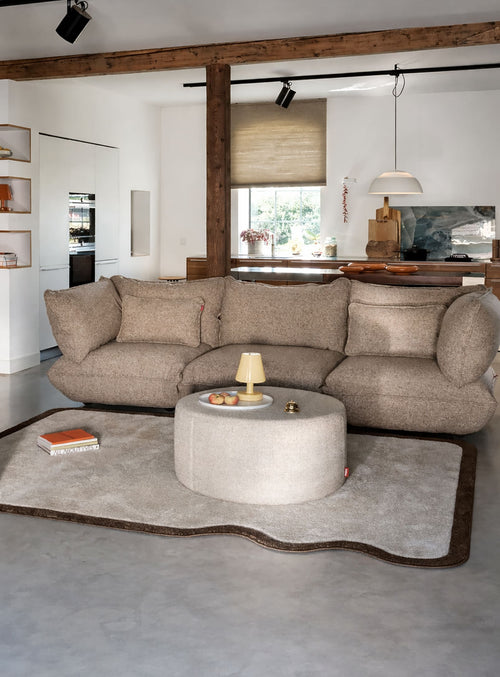 Tapis intérieur compact aux coins arrondis et au bord ondulé, dans une palette crème et brun douce et apaisante.